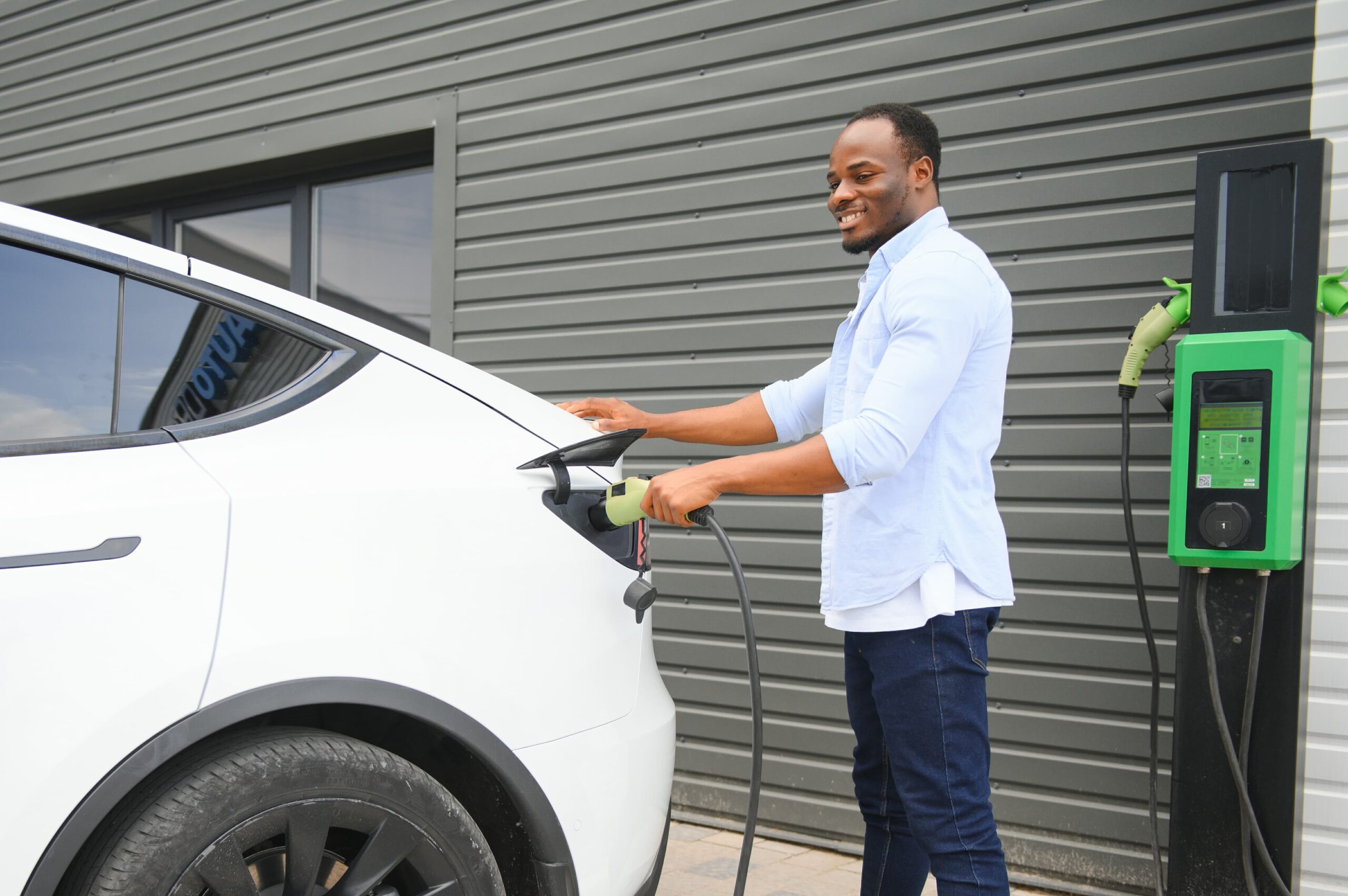 african american man charging his electric car