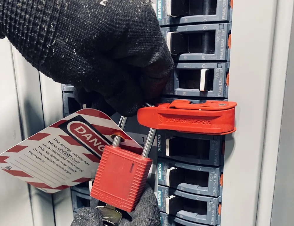 Electrician placing a lockout device on a single breaker in a panel before working on it