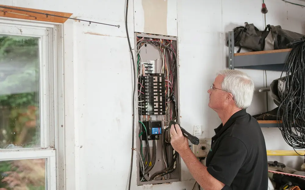 Electrician checking the wiring in an older home panel while sizing a Phoenix-area panel upgrade