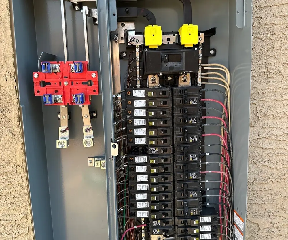 Open main panel with a service disconnect and rows of breakers on a stucco wall at a Phoenix-area home
