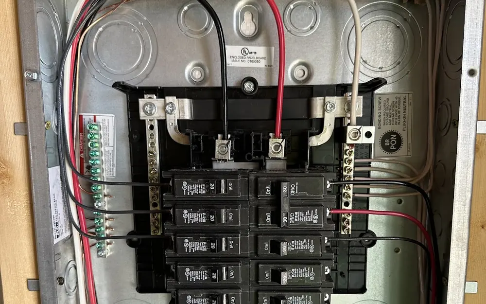 Breaker panel with red and black conductors landed on individual breakers during a panel replacement