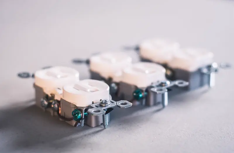 Three white outlets with screw terminals on a gray surface