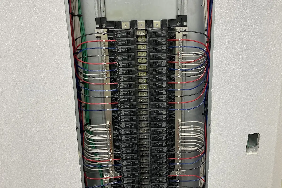 Tall panel with a bundle of wires landed on rows of breakers