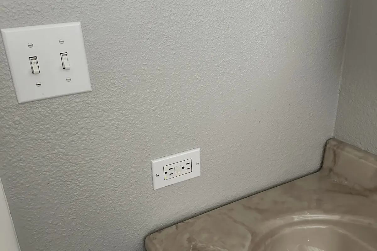 Wall switch and outlet beside a bathroom vanity